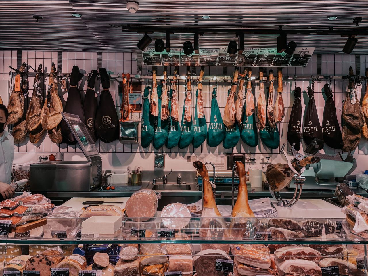 about-02 Explore a bustling butcher shop showcasing a diverse array of cured meats and hams.