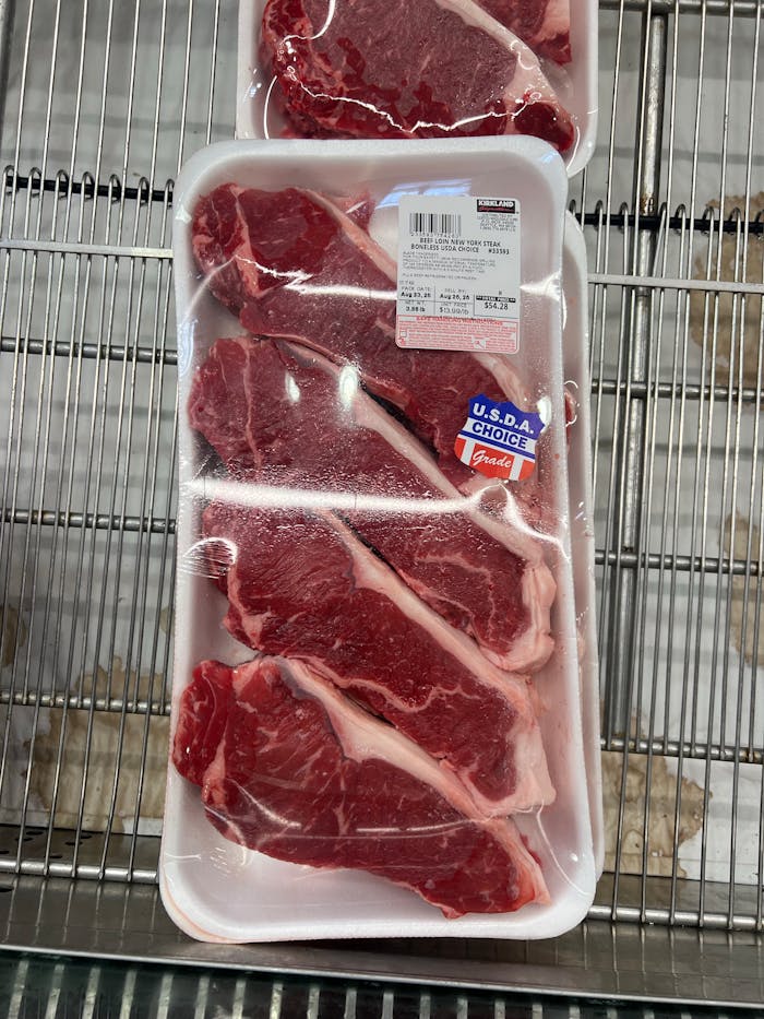 Packaged USDA Choice beef steaks on supermarket shelf, ready for purchase.