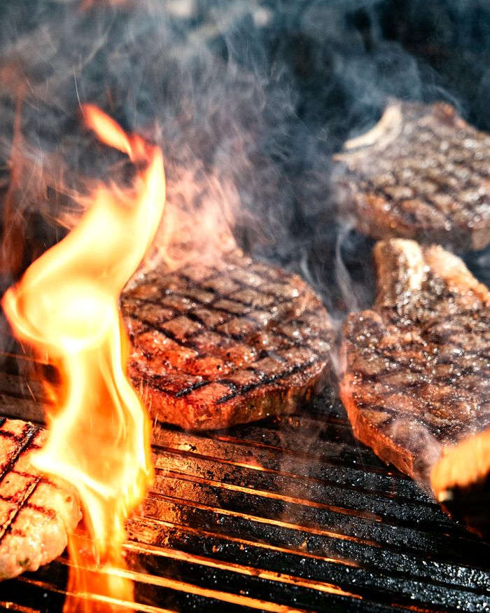 ours-journey Sizzling steaks grilling over an open flame, perfect for summer barbecues and outdoor cooking themes.
